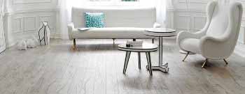 Bild Produkte: Ein modernes Wohnzimmer mit einem weißen Sofa, einem stilvollen Sessel auf einem hellen Laminat.