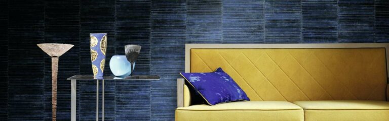 Bild Vliestapete - Ein modernes Wohnzimmer mit einer gelben Couch mit blauen Kissen, vor einer Wand tapeziert mit blauer Vliestapete.