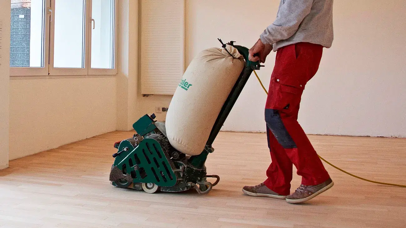 Bild Parkettaufbereitung -Ein Fachmann schleift einen Holzboden mit einem Bodenschleifgerät.